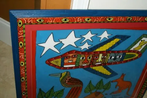 RARE UNIQUE COLORFUL  FOLK ART PAINTING PAPUA NEW GUINEA HUMOROUS ARTIST: TRIBAL WARRIORS TRAVELLING BY AIRPLANE & FRAMED IN SIGNED HAND PAINTED FRAME TO MATCH THE ART DESIGNER COLLECTOR WALL CARTOON  ART  26 1/2” by 23 1/2” HUGE DFP8